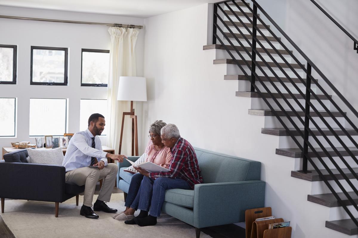 Senior couple meeting in their home with their reverse mortgage loan officer discussing closing documents.